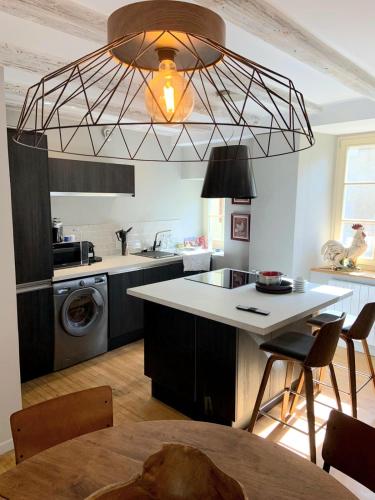 une cuisine avec un grand lustre au-dessus d'un comptoir de cuisine dans l'établissement Charmante petite maison avec baignoire Balneo et video projecteur, à Chaudes-Aigues