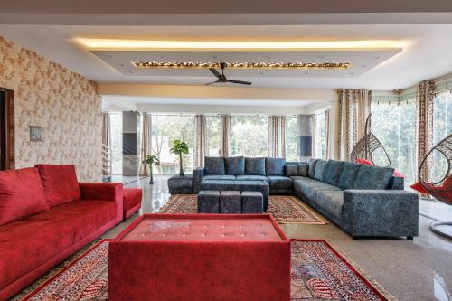 a living room with couches and a red couch at Villa Exotica by StayJade5bhkPoolACProjector in Denkanikota