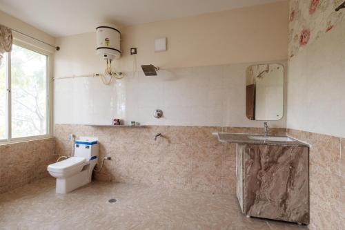 a bathroom with a toilet and a sink at Villa Exotica by StayJade5bhkPoolACProjector in Denkanikota