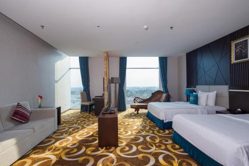 a hotel room with two beds and a couch at The Mira Hotel in Thu Dau Mot