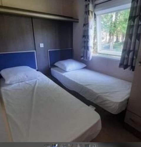deux lits dans une chambre avec une fenêtre dans l'établissement Mobil-Home de Matthieu & Elisa, à Pont-Scorff