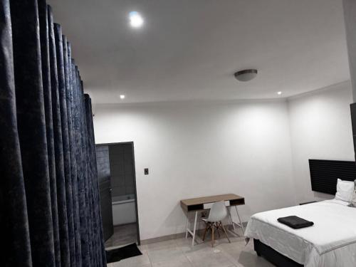 a bedroom with a bed and a desk and curtains at El-Gibbor Residence 1 in Ermelo