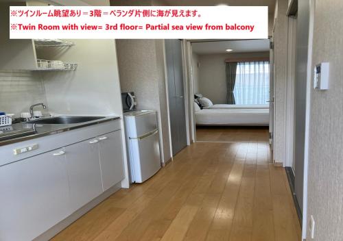 a kitchen with white cabinets and a sink in a room at YANBARU STAY ちゅら宿 in Nago