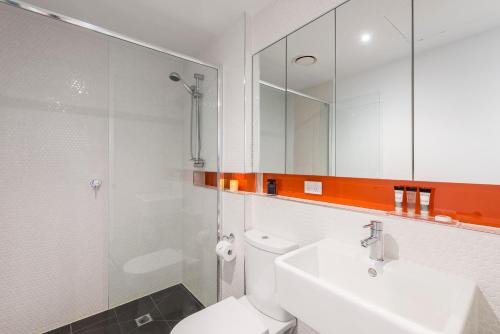 a bathroom with a toilet and a sink and a mirror at Oaks Melbourne South Yarra Suites in Melbourne