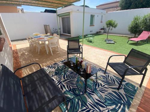 un patio avec une table et des chaises dans une cour dans l'établissement Maison plus studio attenant tout équipé de plain pied climatisé 6CRSUD, à Canet