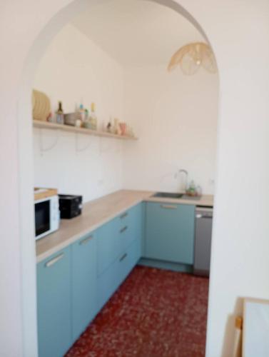 - une cuisine avec des placards bleus et un four micro-ondes dans l'établissement Maison plus studio attenant tout équipé de plain pied climatisé 6CRSUD, à Canet