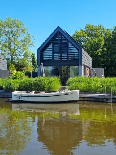 a boat sitting on the water in front of a house at Lutz Watervilla's Balk in Balk
