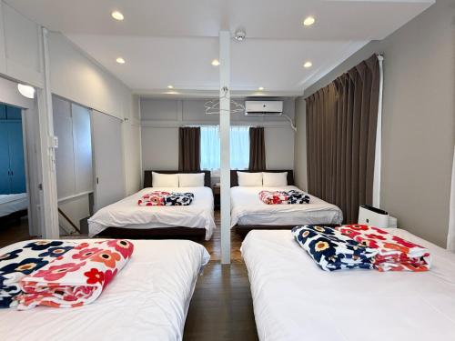 a room with three beds with pillows on them at TABISAI HOTEL House 博多 in Fukuoka