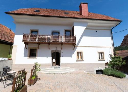 a white house with a balcony and a patio at Velika Hiša in Rašica
