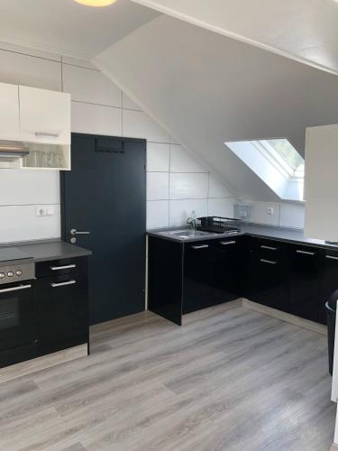 a large kitchen with black cabinets and a skylight at Appartement mansardé 2 chambres in Roth