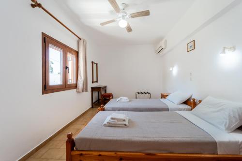 two beds in a white room with a window at Maria Apartments in Pefki Rhodes