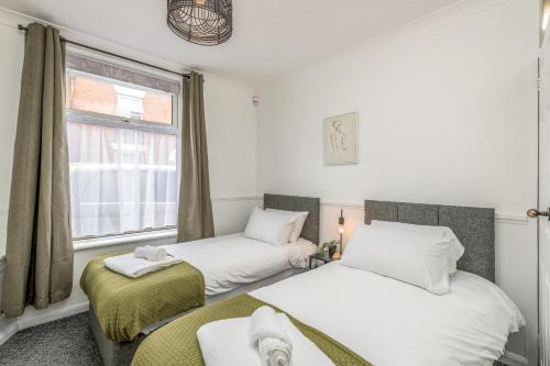 two beds in a room with a window at Wood House by Holmesdale Homes in Kettering