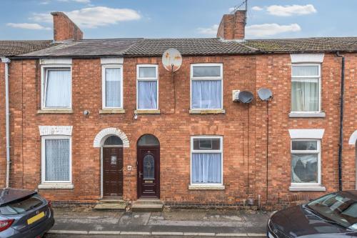 an old brick house with cars parked in front of it at Wood House by Holmesdale Homes in Kettering