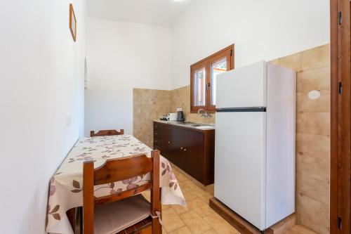 a kitchen with a white refrigerator and a table and chairs at Maria Apartments in Pefki Rhodes