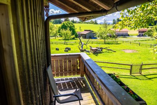 a porch with a chair and a view of a field at Thalerbauer Ferienwohnungen in Wackersberg