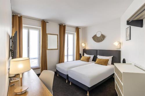 a hotel room with two beds and a table at Best Western Aramis Saint Germain in Paris