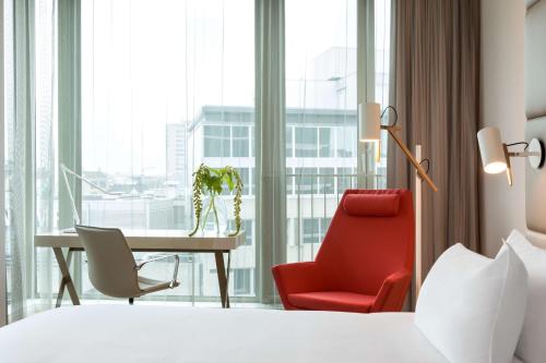 a hotel room with a desk and a red chair at NH Collection Eindhoven Centre in Eindhoven