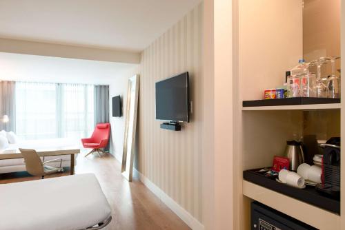 a hotel room with a bed and a table and a tv at NH Collection Eindhoven Centre in Eindhoven