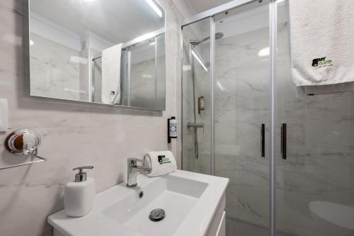 a white bathroom with a sink and a shower at BmyGuest - Sesimbra Central Apartment in Sesimbra