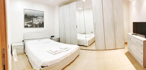 a white bedroom with a bed and a mirror at A casa dei nonni in San Felice a Cancello