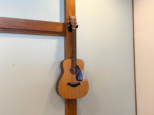a wooden guitar hanging on a wall at TABISAI HOTEL House 博多 in Fukuoka