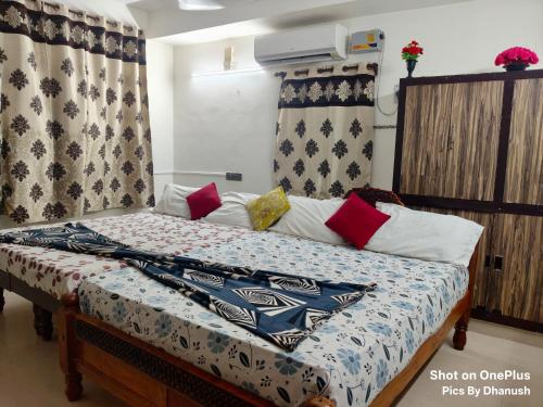 a bed with colorful pillows and avertisement at Annamaiah Guest House & Homestay - Tirupati - Home Food Service in Tirupati