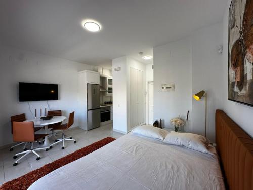ein weißes Schlafzimmer mit einem großen Bett und einem Schreibtisch in der Unterkunft Magnificent Studio Isla Cristina in Isla Cristina