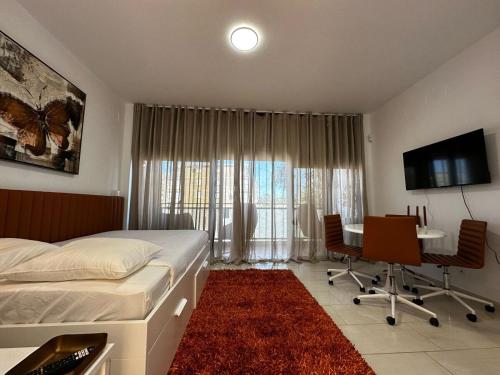 ein Schlafzimmer mit einem Bett, einem Schreibtisch und einem Fernseher in der Unterkunft Magnificent Studio Isla Cristina in Isla Cristina