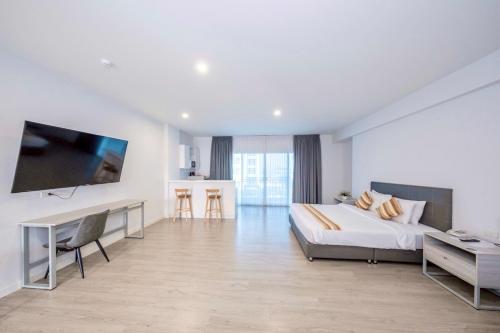 a white bedroom with a large bed and a television at GRAND PA Hotel&Resort Lamphun Chiang Mai in Lamphun