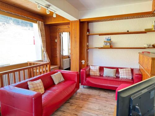 - un salon avec deux canapés rouges et une télévision dans l'établissement Appartement cosy 8 pers avec terrasse, proche des pistes, Les Gets - FR-1-623-368, aux Gets