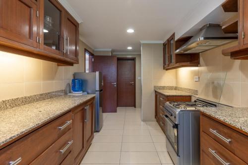 a kitchen with wooden cabinets and a stove top oven at Riverside Park Tropical Oasis 3B YourHost Nairobi in Nairobi
