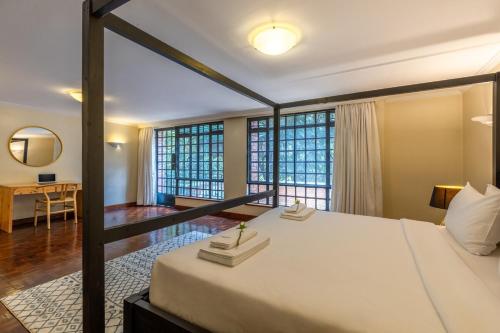 a bedroom with a large bed and some windows at Riverside Park Tropical Oasis 3B YourHost Nairobi in Nairobi