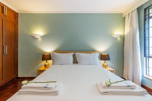 a bedroom with a large white bed with two lamps at Riverside Park Tropical Oasis 3B YourHost Nairobi in Nairobi