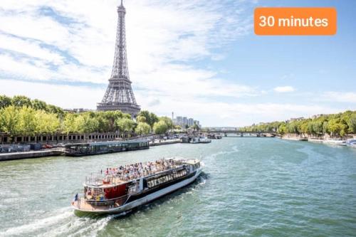 a boat on a river in front of the eiffel tower at Apartement Duplex proche Paris, Aéroport CDG Stade de France Parc Expo Villepinte in Le Blanc-Mesnil