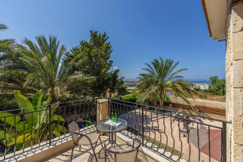 a balcony with a table and chairs and palm trees at Villa Agathi in Argaka