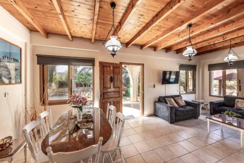 a living room with a wooden ceiling and a glass table at Villa Agathi in Argaka