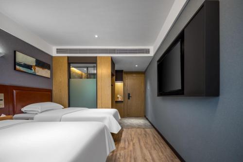 a bedroom with two beds and a flat screen tv at Weiting Light Hotel Shanghai University of Finance and Economics in Shanghai