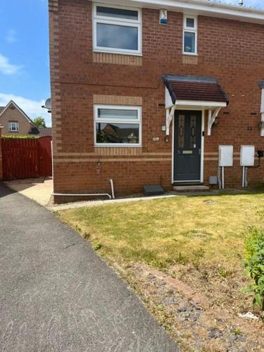 a brick house with a black door and a yard at Barrowburn Green in Yarm