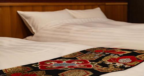 a white bed with a patterned blanket on it at Ubusuna no Sato TOMIMOTO in Ando