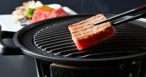 a piece of fish is cooking on a grill at Ubusuna no Sato TOMIMOTO in Ando