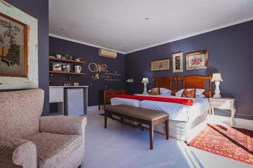 a bedroom with a bed and a couch and a chair at Acorn Guest House in George
