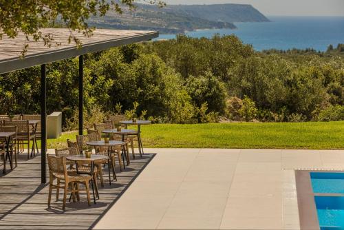 a row of tables and chairs next to a swimming pool at Rodi Studios in Karavadhos