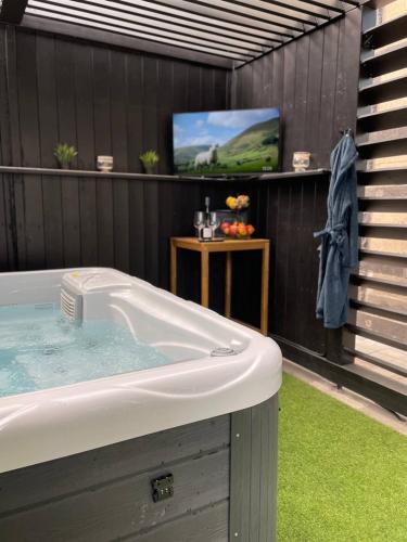 a bathroom with a tub and a tv on a wall at Bahnhofsoase - Wellness & Spa am Krufter Bahnhof in Kruft