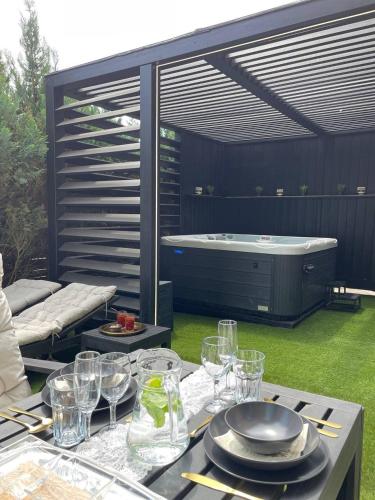 a table with plates and glasses on a patio with a tub at Bahnhofsoase - Wellness & Spa am Krufter Bahnhof in Kruft
