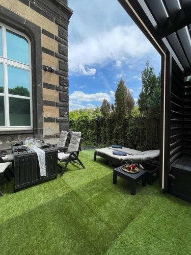 a patio with a lawn with chairs and a table at Bahnhofsoase - Wellness & Spa am Krufter Bahnhof in Kruft