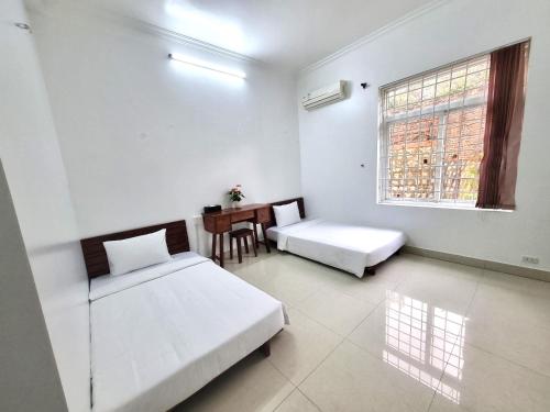 a white room with two beds and a table at Top Hill Halong in Ha Long