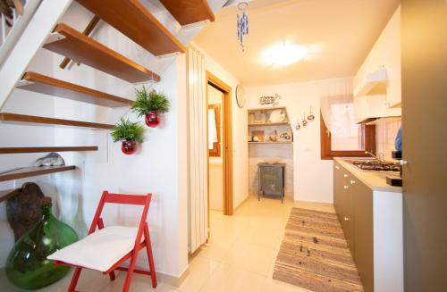 a kitchen with a red chair and a table at Dimora Rubino - Isola di Pellestrina Ve in Pellestrina
