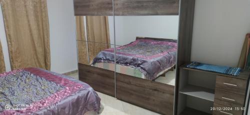 een slaapkamer met een spiegelkast met een bed bij appartement T3 équipe in Matriouene