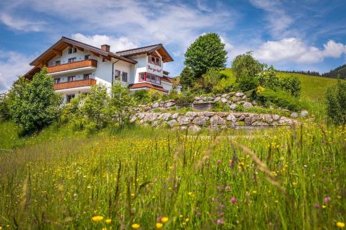 a house on a hill with a field of flowers at Bergerhof in Ramsau am Dachstein