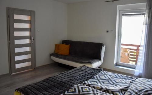 a bedroom with a bed and a couch and a window at Apartmán u Braňa in Telgárt